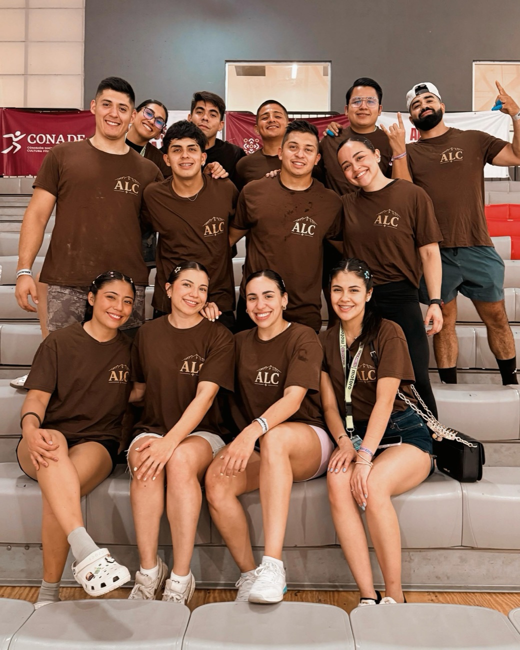 Equipo de ALC Power Strength con sus playeras cafés en la grada de una competencia nacional