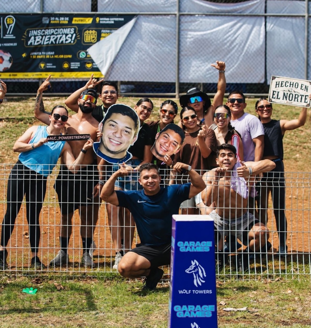 Atletas de ALC animando desde la valla con el letrero Hecho en el Norte