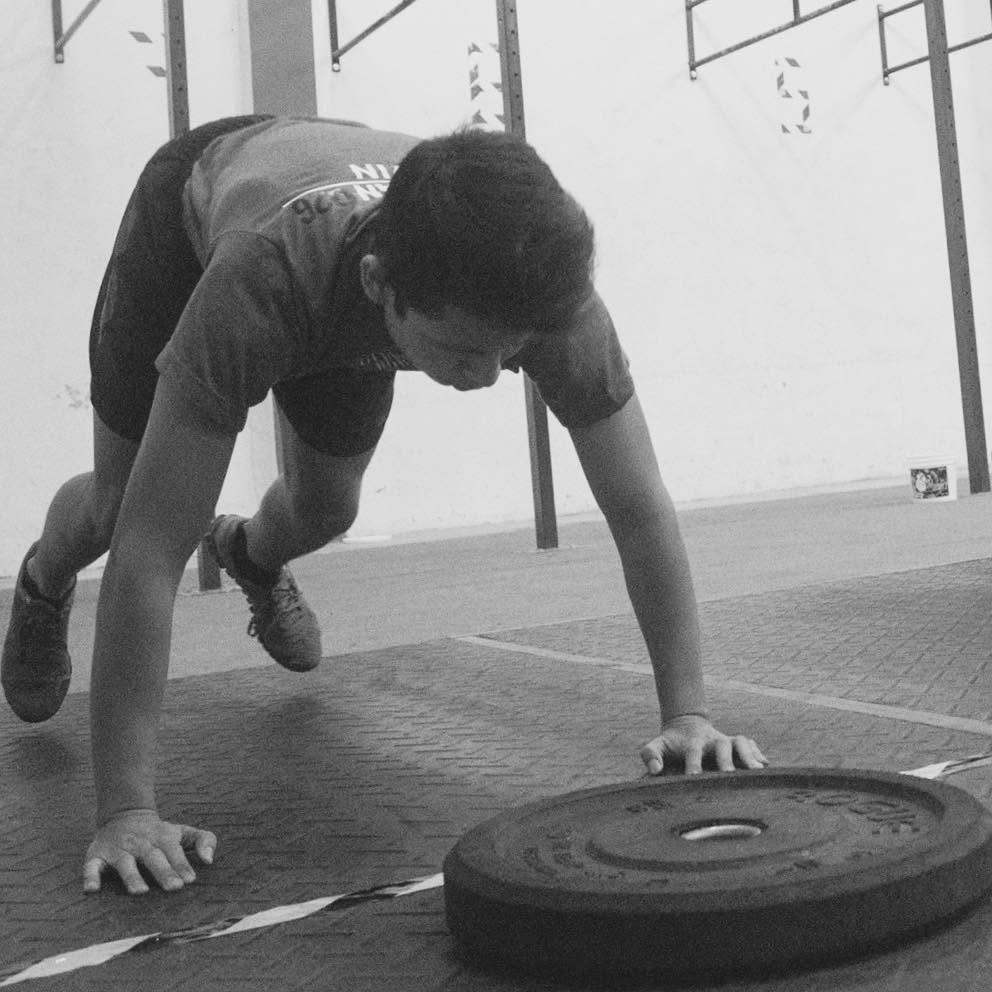 Cristian Ibarra compitiendo en su primera competencia de CrossFit, junto a un disco de pesas